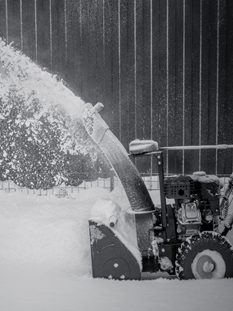 Snowblower throwing a wide spray of snow into the air during winter clearing.