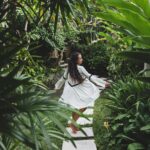 Woman walking through lush tropical garden with manicured pathway