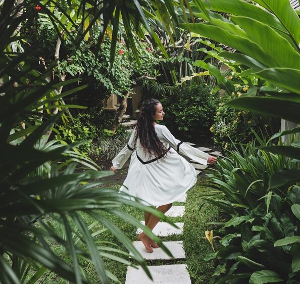 Woman walking through lush tropical garden with manicured pathway